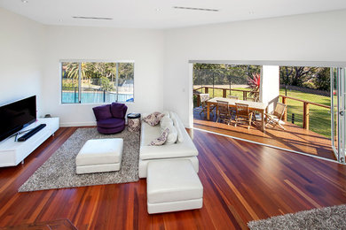 Photo of a large open concept living room in Sydney with grey walls, medium hardwood floors and a freestanding tv.