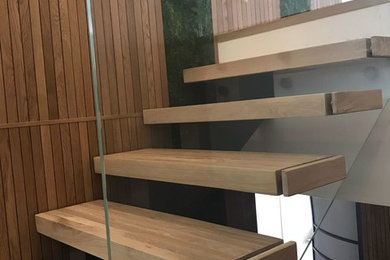 Стильный дизайн: маленькая п-образная лестница в современном стиле с деревянными ступенями и стеклянными перилами для на участке и в саду - последний тренд