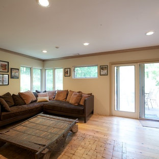 Large modern study in Philadelphia with beige walls, light hardwood flooring, a corner fireplace, a plastered fireplace surround and a freestanding desk.