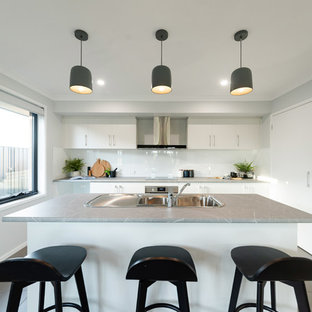 This is an example of a mid-sized contemporary galley kitchen pantry in Hobart with a double-bowl sink, shaker cabinets, white cabinets, laminate benchtops, white splashback, ceramic splashback, stainless steel appliances, cement tiles, with island, grey floor and grey benchtop.