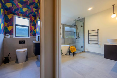 На фото: детский совмещенный санузел среднего размера в современном стиле с черными фасадами, отдельно стоящей ванной, угловым душем, раздельным унитазом, желтой плиткой, керамогранитной плиткой, серыми стенами, полом из керамогранита, настольной раковиной, столешницей из искусственного кварца, серым полом, душем с распашными дверями, белой столешницей, тумбой под две раковины, подвесной тумбой, потолком с обоями и обоями на стенах с
