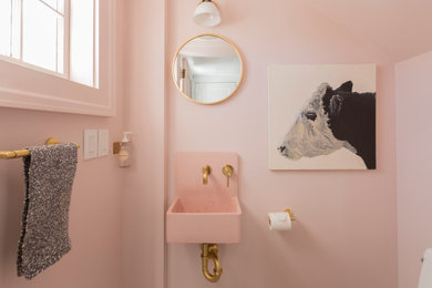 Small contemporary powder room in New York with pink walls, a wall-mount sink and pink benchtops.
