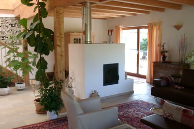 This is an example of a contemporary open concept living room in Munich with white walls, ceramic floors, a wood stove and a plaster fireplace surround.