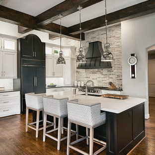 Ejemplo de cocina en L, tradicional, extra grande, con suelo de madera oscura, una isla, fregadero de doble seno, armarios con paneles empotrados, puertas de armario negras, salpicadero verde, electrodomésticos con paneles y suelo marrón