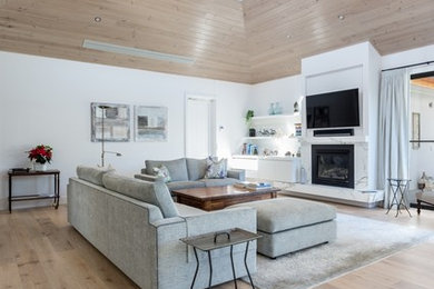 Photo of a mid-sized beach style open concept living room in Geelong with grey walls, light hardwood floors, a standard fireplace, a stone fireplace surround, grey floor and a wall-mounted tv.