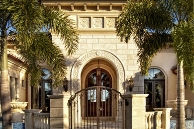 Large tuscan beige one-story stucco exterior home photo in Miami