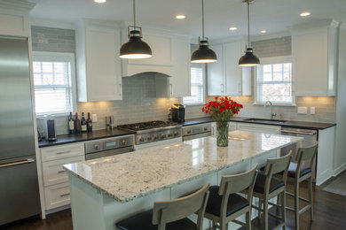 Inspiration for a large timeless dark wood floor and brown floor open concept kitchen remodel in Minneapolis with a double-bowl sink, flat-panel cabinets, white cabinets, granite countertops, gray backsplash, subway tile backsplash, stainless steel appliances, an island and white countertops