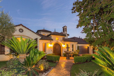 Large mediterranean beige one-story stucco exterior home idea in Other with a hip roof