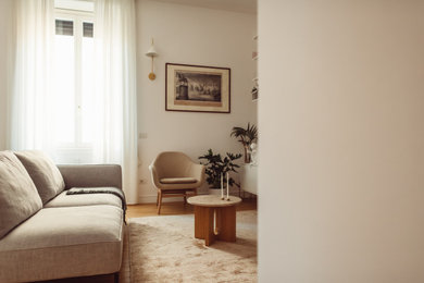 Esempio di un soggiorno design di medie dimensioni e aperto con libreria, pareti bianche, pavimento in legno verniciato, TV a parete, pavimento marrone e tappeto