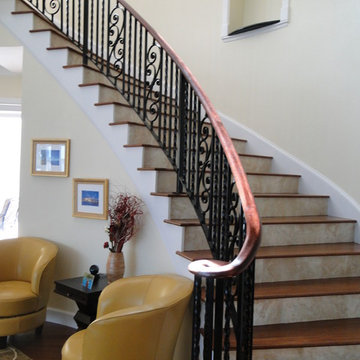 Interior wrought iron stair rail with lateral scroll ending and wood cap