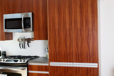 Kitchen pantry - mid-sized contemporary l-shaped light wood floor kitchen pantry idea in Other with a farmhouse sink, flat-panel cabinets, medium tone wood cabinets, granite countertops, stainless steel appliances and an island