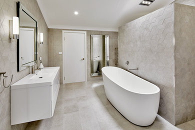 Photo of a large contemporary master bathroom in Sydney with furniture-like cabinets, white cabinets, a freestanding tub, an open shower, a one-piece toilet, beige tile, porcelain tile, beige walls, porcelain floors, an integrated sink, engineered quartz benchtops, beige floor and an open shower.