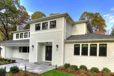 Example of a large trendy white two-story concrete house exterior design in New York with a hip roof and a shingle roof