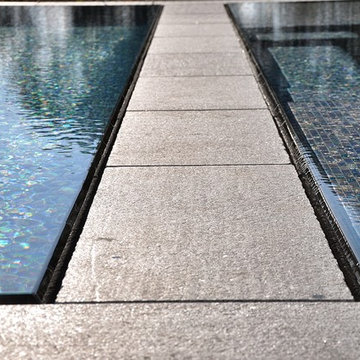 glass tile swimming pool + spa with perimeter overflow + granite decking