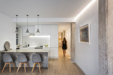 Design ideas for a mid-sized modern single-wall open plan kitchen in Valencia with quartz benchtops, white appliances, brown floor, white benchtop and with island.