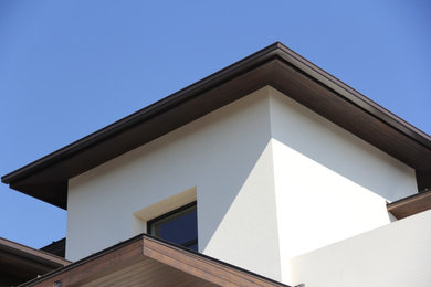 Example of a large minimalist white two-story stucco house exterior design in Oklahoma City with a hip roof and a shingle roof
