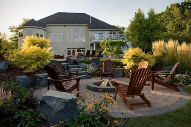 Inspiration for a mid-sized traditional backyard patio in Minneapolis with a fire feature, brick pavers and no cover.