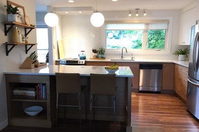 Mid-sized minimalist l-shaped laminate floor and brown floor eat-in kitchen photo in Calgary with an undermount sink, flat-panel cabinets, light wood cabinets, quartz countertops, white backsplash, subway tile backsplash, stainless steel appliances, a peninsula and white countertops
