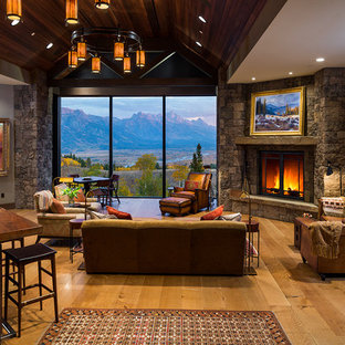 Ejemplo de salón abierto, rural, grande, sin televisor, con suelo de madera en tonos medios, chimenea tradicional, marco de chimenea de piedra, paredes beige y suelo marrón