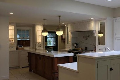 Example of a mid-sized eclectic u-shaped ceramic tile and white floor open concept kitchen design in Boston with a farmhouse sink, shaker cabinets, white cabinets, quartz countertops, black appliances and two islands