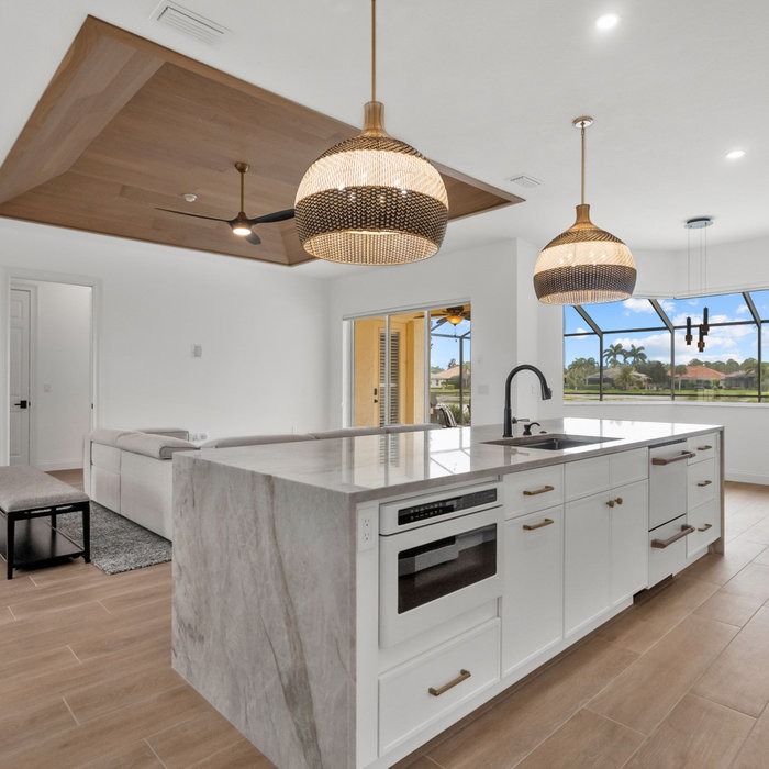 Luxury kitchen remodel in Venice, FL (Sarasota County) featuring a waterfall quartz island, custom wood ceiling detail, and open-concept modern coastal design.