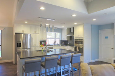 Inspiration for a mid-sized contemporary l-shaped medium tone wood floor open concept kitchen remodel in Dallas with an undermount sink, raised-panel cabinets, white cabinets, quartzite countertops, black backsplash, subway tile backsplash, stainless steel appliances and an island