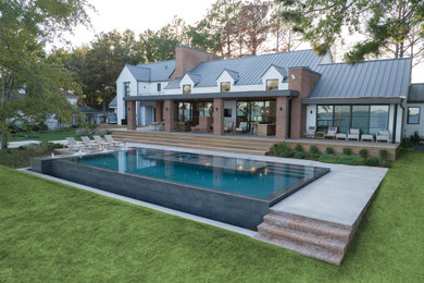 Large minimalist backyard stone and rectangular infinity pool landscaping photo in Dallas