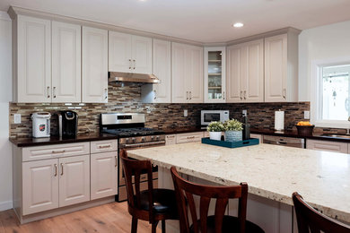 Inspiration for a large contemporary l-shaped light wood floor and brown floor eat-in kitchen remodel in Los Angeles with a drop-in sink, raised-panel cabinets, gray cabinets, granite countertops, multicolored backsplash, glass tile backsplash, stainless steel appliances, an island and multicolored countertops