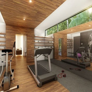 マイアミの巨大なトロピカルスタイルのおしゃれな多目的ジム (白い壁、無垢フローリング、茶色い床) の写真