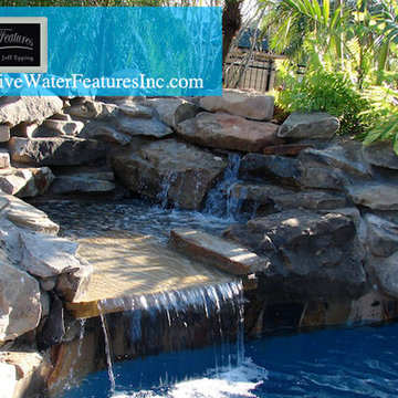Tropical backyard room with pool waterfall, fireplace, and koi pond