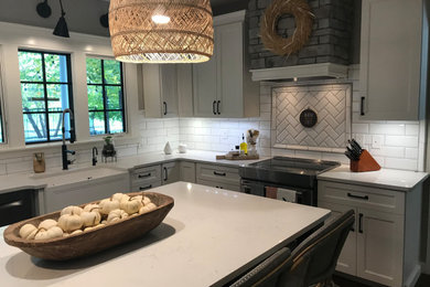 Inspiration for a mid-sized country u-shaped eat-in kitchen in Cleveland with a farmhouse sink, flat-panel cabinets, white cabinets, quartz benchtops, white splashback, subway tile splashback, stainless steel appliances, dark hardwood floors, brown floor, white benchtop and with island.