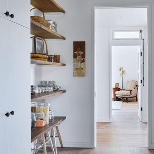 Idées déco pour une arrière-cuisine linéaire scandinave avec un placard à porte plane, des portes de placard blanches, un sol en bois brun et un sol marron.