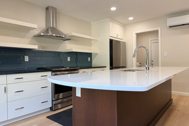 Eat-in kitchen - large eat-in kitchen idea in DC Metro with an undermount sink, flat-panel cabinets, blue backsplash, subway tile backsplash, stainless steel appliances, an island, white cabinets, quartz countertops and white countertops