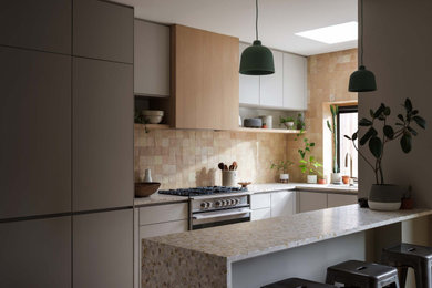 Example of a mid-sized trendy u-shaped eat-in kitchen design in New York with flat-panel cabinets, gray cabinets, terrazzo countertops, ceramic backsplash and a peninsula
