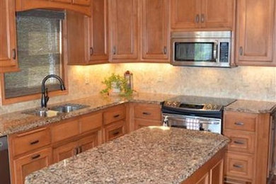 Inspiration for a mid-sized timeless l-shaped medium tone wood floor enclosed kitchen remodel in Minneapolis with a double-bowl sink, raised-panel cabinets, medium tone wood cabinets, granite countertops, beige backsplash, stone tile backsplash, stainless steel appliances and an island