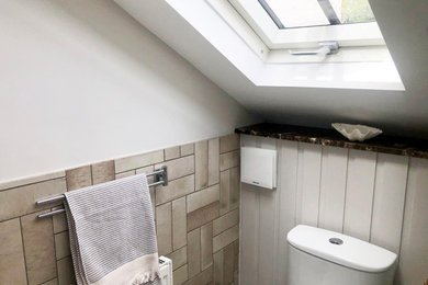 Photo of a small contemporary grey and brown half tiled bathroom in London with a bidet, beige tiles, ceramic tiles, beige walls, ceramic flooring, a wall-mounted sink, grey floors, brown worktops, a feature wall, a single sink and a floating vanity unit.