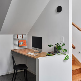 This is an example of a small beach style study room in Sunshine Coast with white walls, no fireplace, a built-in desk and grey floor.