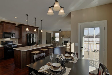 Kitchen - large traditional medium tone wood floor kitchen idea in Chicago with brown cabinets, granite countertops, black appliances and an island