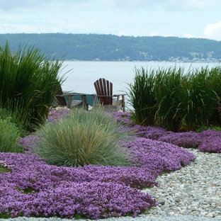 Small beach style backyard full sun xeriscape in Seattle with with flowerbed and river rock for summer.