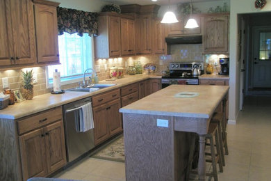 Eat-in kitchen - mid-sized traditional galley ceramic tile and beige floor eat-in kitchen idea in Other with a drop-in sink, raised-panel cabinets, medium tone wood cabinets, limestone countertops, beige backsplash, ceramic backsplash, stainless steel appliances and an island