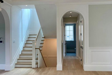 Large arts and crafts open concept light wood floor, coffered ceiling and wainscoting living room photo in Vancouver with white walls and a standard fireplace