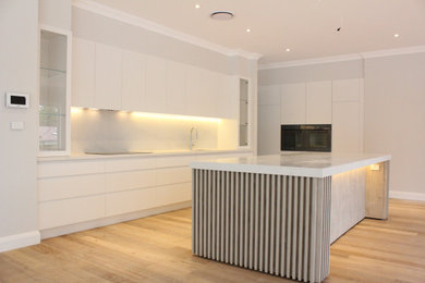 Design ideas for a large modern eat-in kitchen in Sydney with an undermount sink, white cabinets, quartz benchtops, white splashback, stone slab splashback, panelled appliances, with island and white benchtop.