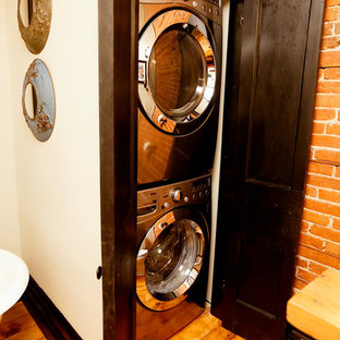 Foto de armario lavadero lineal, clásico renovado, pequeño, con armarios estilo shaker, puertas de armario de madera en tonos medios, paredes blancas, suelo de madera clara y lavadora y secadora apiladas