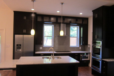 Trendy l-shaped eat-in kitchen photo in Dallas with an undermount sink, dark wood cabinets, granite countertops, glass tile backsplash and stainless steel appliances