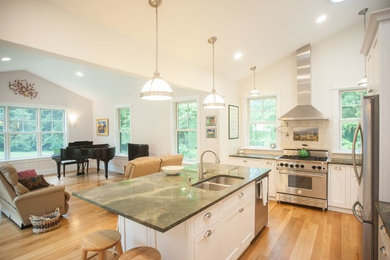 Example of a mid-sized transitional l-shaped medium tone wood floor and beige floor open concept kitchen design in Boston with an undermount sink, beaded inset cabinets, yellow cabinets, marble countertops, beige backsplash, ceramic backsplash, stainless steel appliances and an island