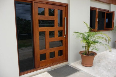 На фото: входная дверь среднего размера в современном стиле с серыми стенами, бетонным полом, поворотной входной дверью и входной дверью из дерева среднего тона