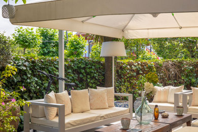 Ejemplo de terraza planta baja tradicional renovada grande en patio trasero con jardín de macetas y toldo