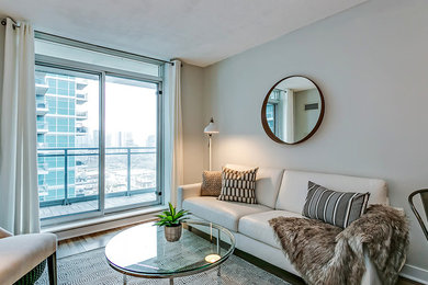 Photo of a small contemporary open concept living room in Toronto with grey walls and light hardwood floors.