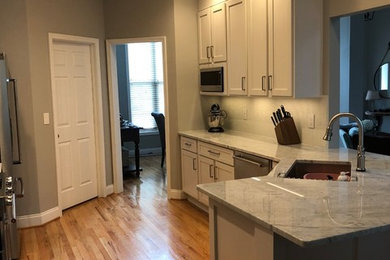 Inspiration for a small transitional u-shaped light wood floor and beige floor kitchen pantry remodel in Charlotte with an undermount sink, shaker cabinets, white cabinets, granite countertops, stainless steel appliances, a peninsula and gray countertops