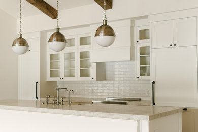 Inspiration for a large transitional single-wall dark wood floor, brown floor and vaulted ceiling open concept kitchen remodel in Other with a farmhouse sink, shaker cabinets, white cabinets, quartzite countertops, white backsplash, ceramic backsplash, stainless steel appliances, an island and beige countertops